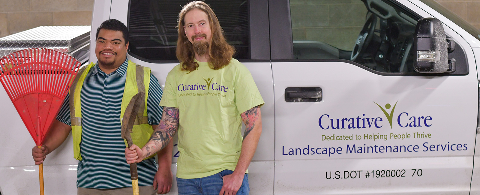 Adult client standing next to landscape supervisor, both holding lawn equipment