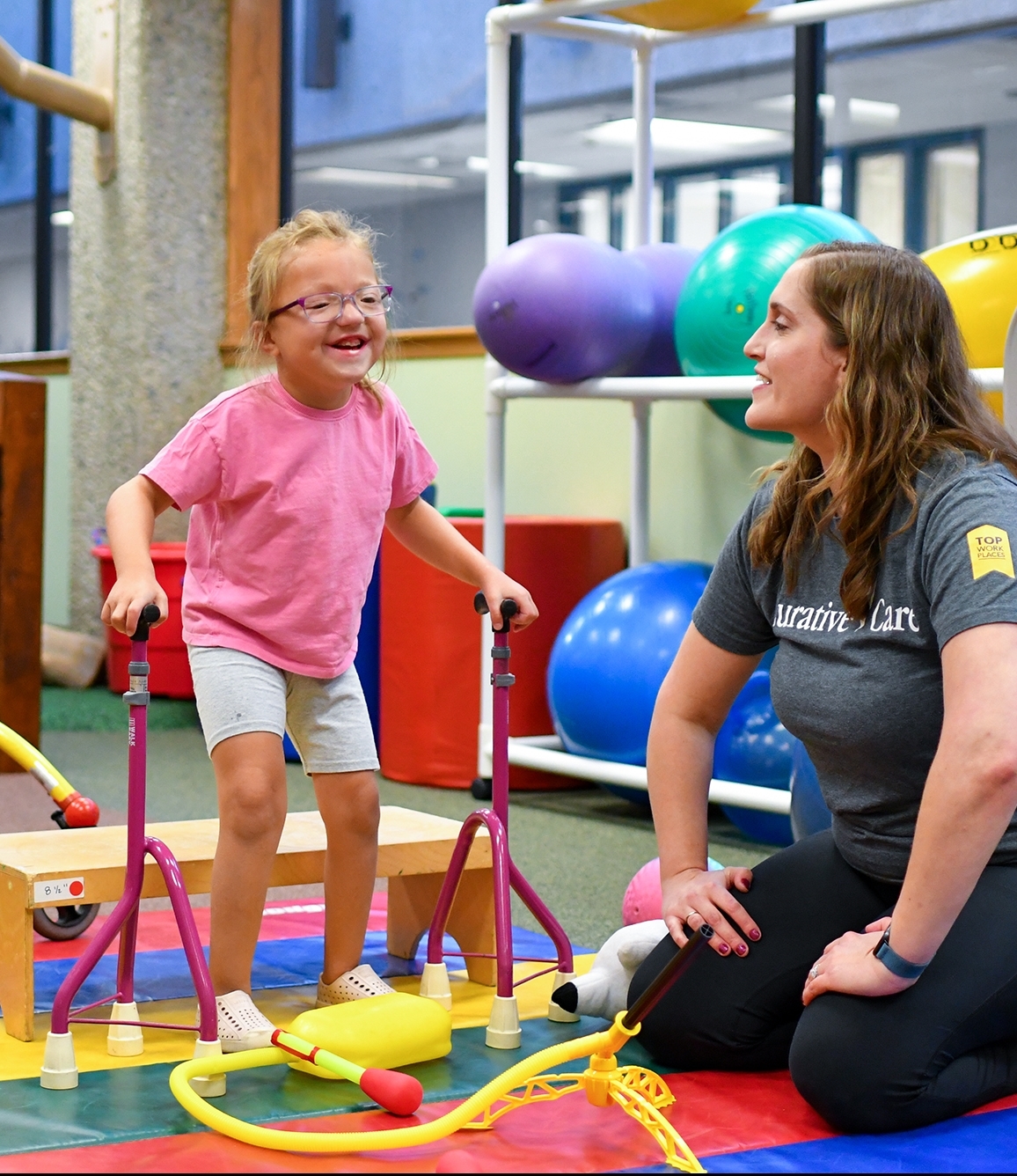 Female therapist with young girl at bottom of jungle gym slide